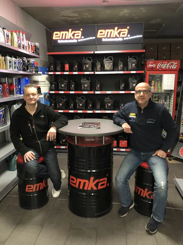 Die beiden Inhaber sitzen im Verkaufsraum an einem Stehtisch aus einem Ölfass